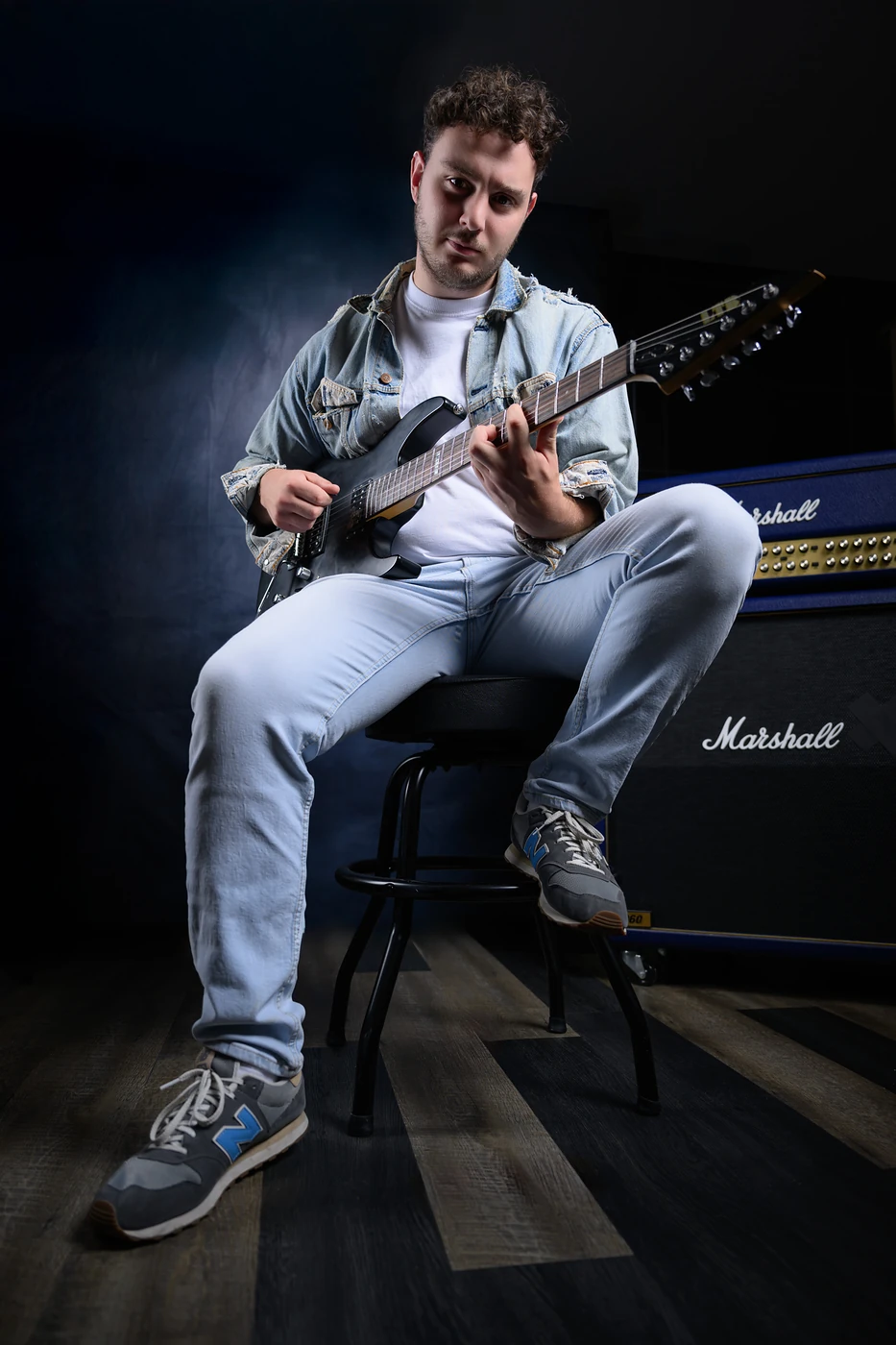 Portrait studio d'un guitariste assis devant un ampli Marshall