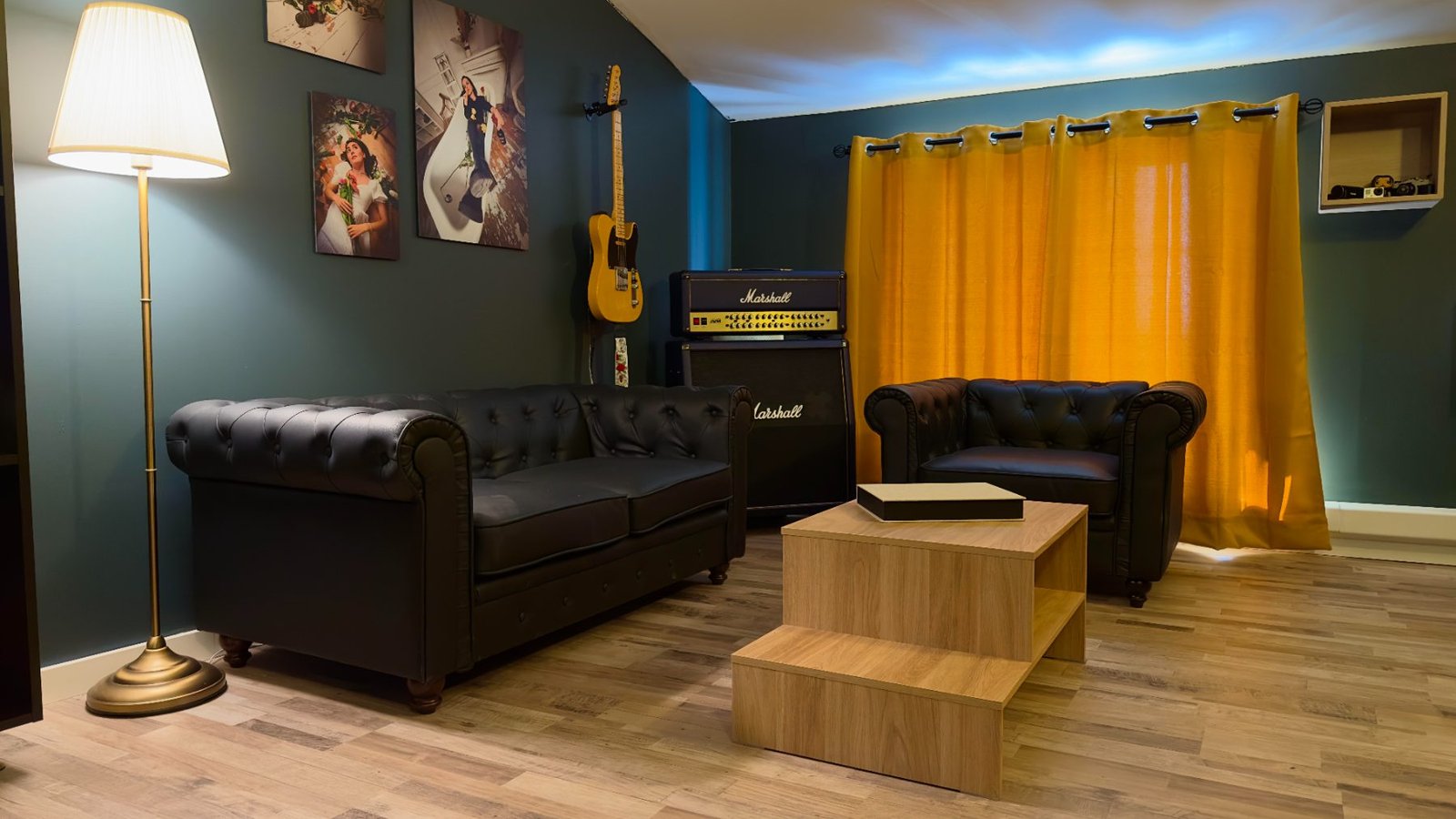 Salon d'attente du studio photo&nbsp;: canapés Chesterfield, tirages encadrés au mur et ampli guitare